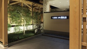 Een receptiezone met een houten constructie, een bord met Chinese karakters en een aangelegde tuin met bomen en een rots.