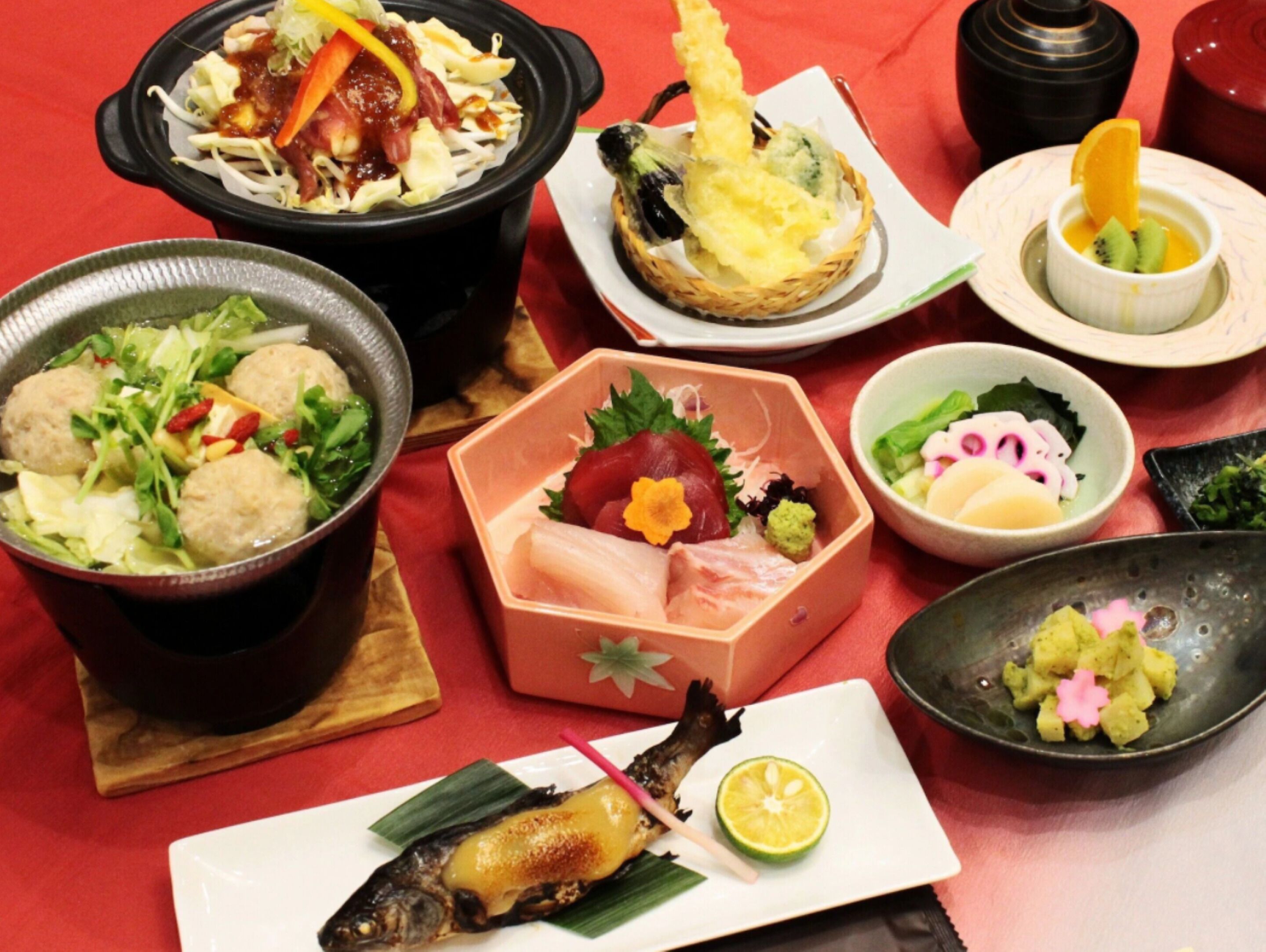 A variety of dishes including a bowl of salad, a plate with a grilled fish, and several other dishes with different garnishes and ingredients.
