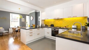 Una cocina moderna con armarios blancos, encimera negra y salpicadero amarillo.