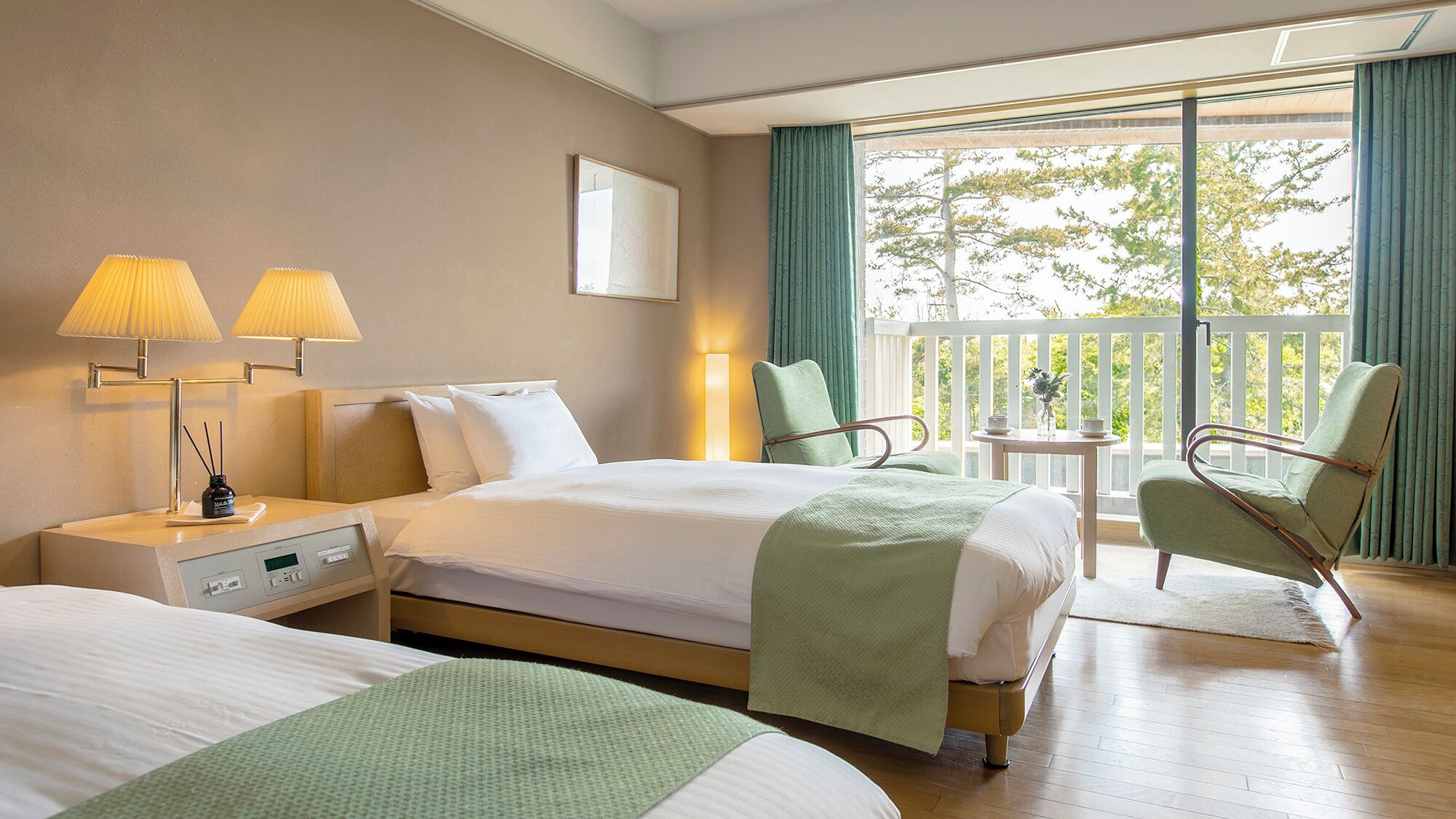 A hotel room with two beds, a nightstand, lamps, a small table with a vase, and a balcony with curtains.
