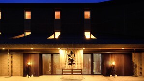 A building with a large entrance, vertical windows, and a sign with characters. - Chirihama Hotel Yubana (Hakui)