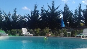 Piscina com espreguiçadeiras e um guarda-sol azul.