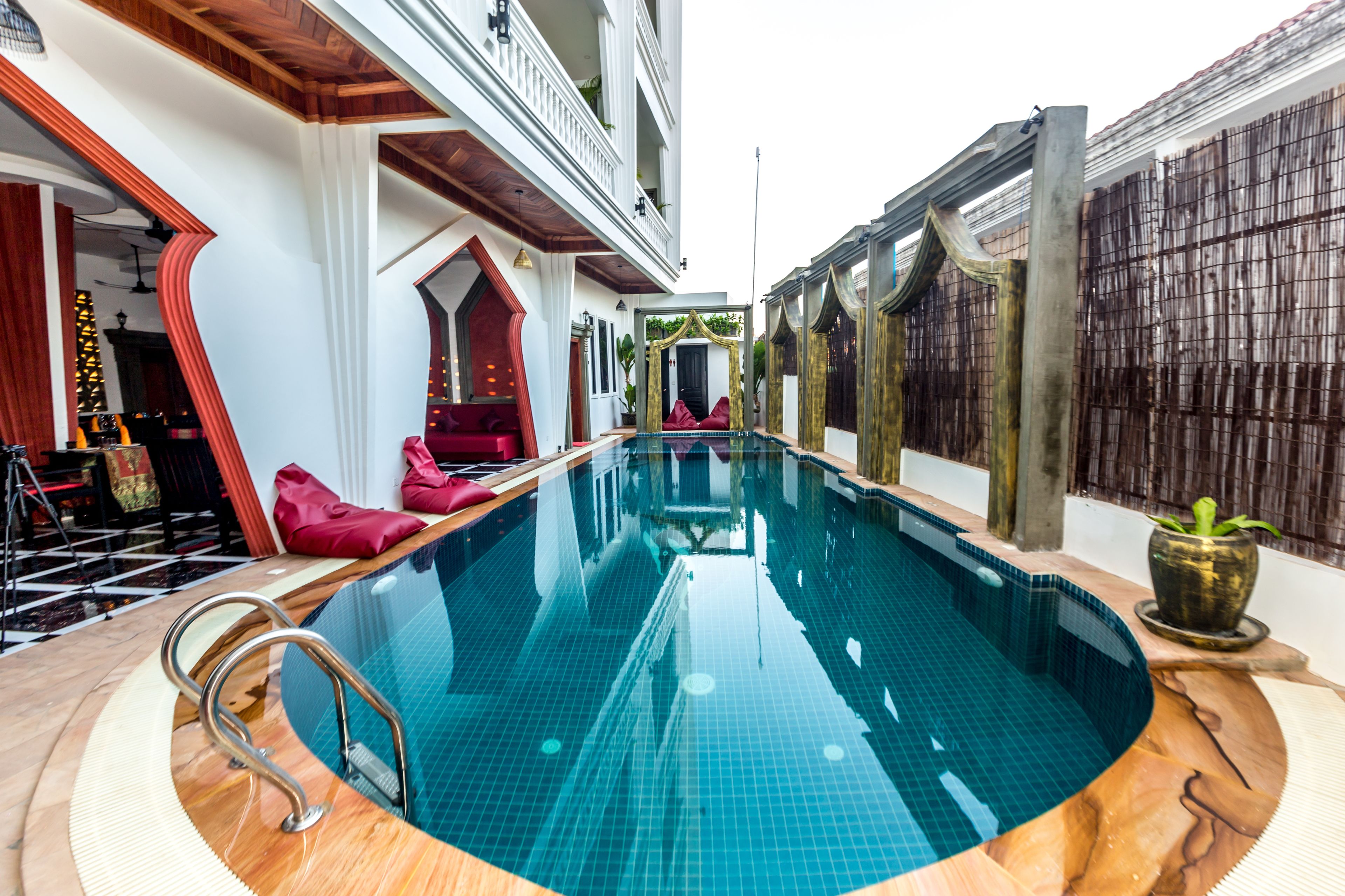 A swimming pool with a wooden deck and a red chair.