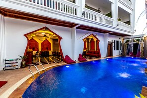 An indoor swimming pool with a red and white architectural design, including a balcony with plants.
