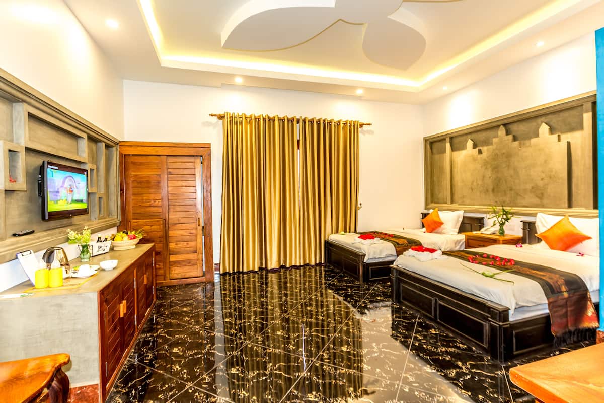 Habitación de hotel con cama, escritorio con televisor, baño y ventana grande con cortinas.