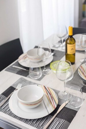 A dining table set with plates, glasses, and a bottle of wine. - Signoria Conte's Suite (Florence)