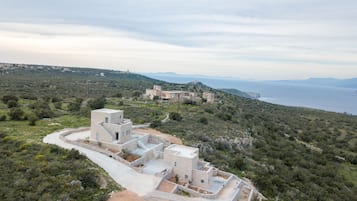 A coastal building complex with multiple structures, surrounded by natural vegetation and a view of the sea.