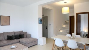 Ein modernes Wohnzimmer mit einer Couch, einem Couchtisch und einem Essbereich mit Stühlen und einem Tisch.