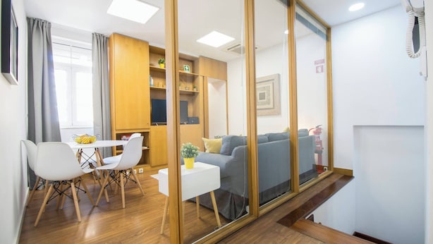 Un salon moderne avec un canapé, une table à manger et des chaises, un téléviseur et des meubles en bois.