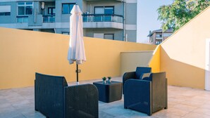 Un espace extérieur aménagé avec des meubles en osier, une petite table et un parasol.