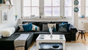 A modern living room with a black sectional sofa, a white coffee table, and a large window with a view of a snowy landscape.