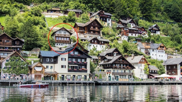 A lakeside village with traditional wooden houses, a dock with boats, and a bridge connecting the buildings to the shore.