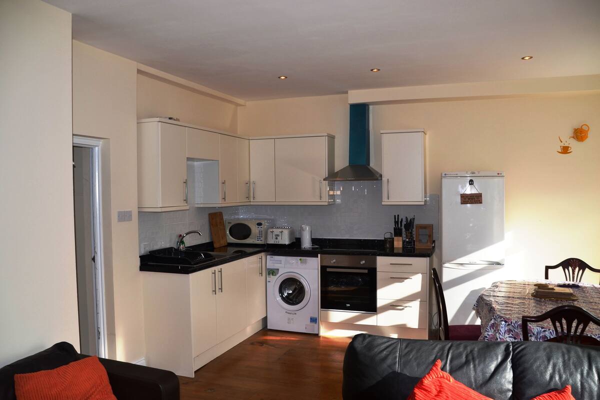 A compact kitchen with a washing machine, microwave, and oven.