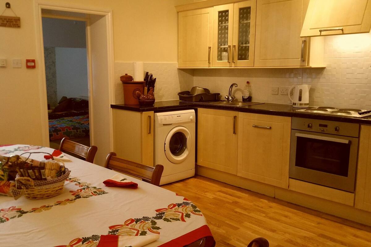 A kitchen with a washing machine, stove, and cabinets.