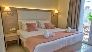 Ein modernes Hotelzimmer mit einem großen Bett, zwei Nachttischlampen, einem Holzkopfstück und Blick ins Freie.