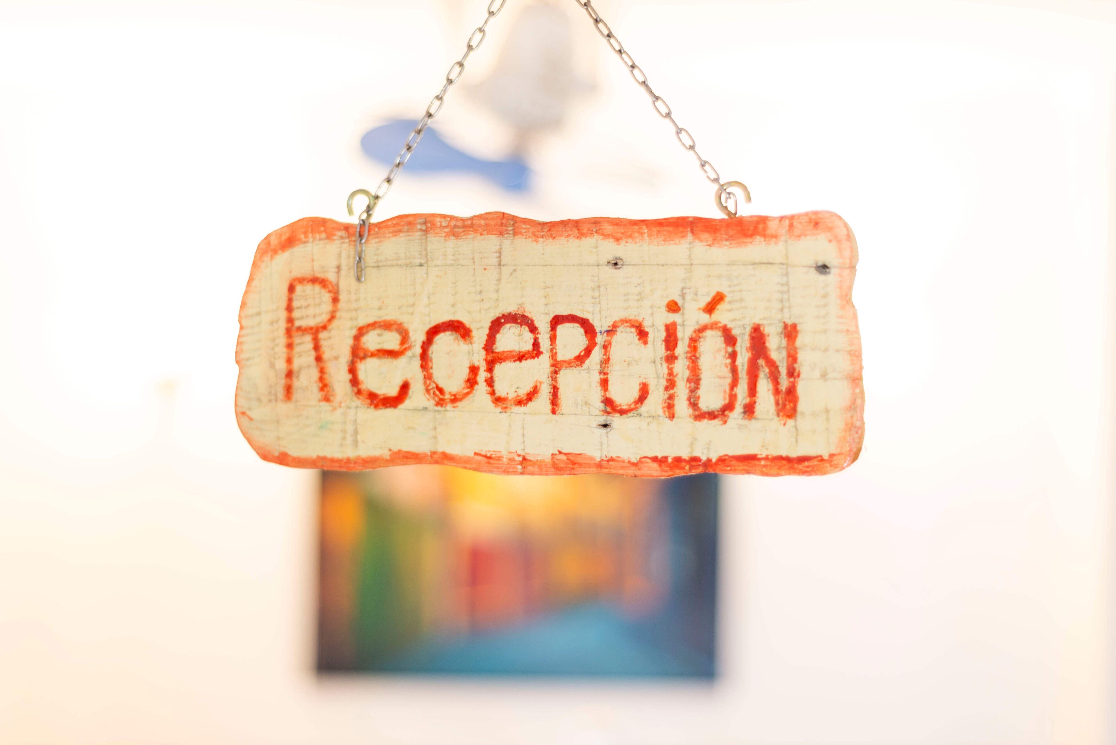 A wooden sign with the word "Recepción" hanging from a chain.