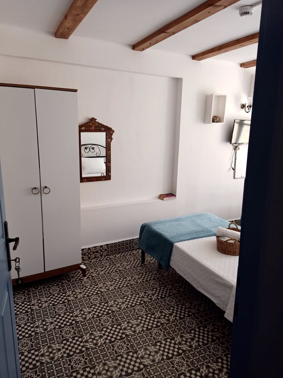 Een slaapkamer met een bed, een kledingkast, een spiegel en een klein plankje.