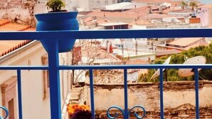 A balcony with a view of a coastal town, a potted plant, and a vase with flowers. - Kelebek Ayvalık (Ayvalik)