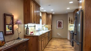 A kitchen with wooden cabinets, a stainless steel refrigerator, a wooden countertop, and a lamp.