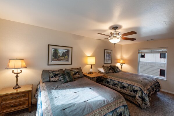 A bedroom with two beds, a ceiling fan, and framed pictures on the wall. - Starlight Lodge (Wawona)
