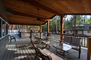 A wooden deck with outdoor seating, a ceiling fan, and a view of a forested area. - Starlight Lodge (Wawona)