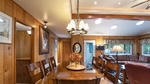 A wooden-paneled dining room with a chandelier, a dining table, and chairs.