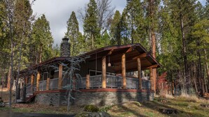 A cabin with a stone foundation, wooden beams, and a porch with a railing.