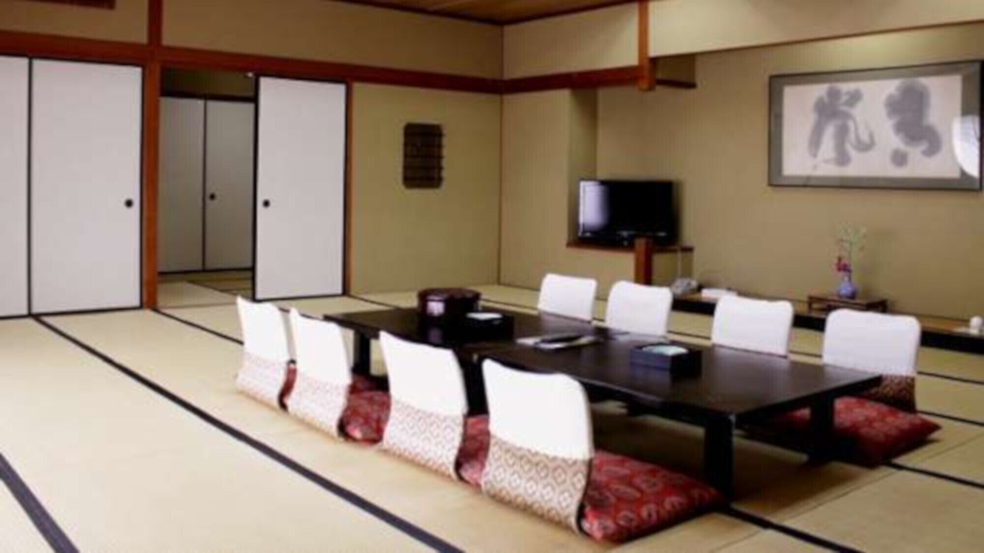 Une pi èce de style japonais traditionnel, avec un sol recouvert de tatamis, une table basse et des chaises blanches.