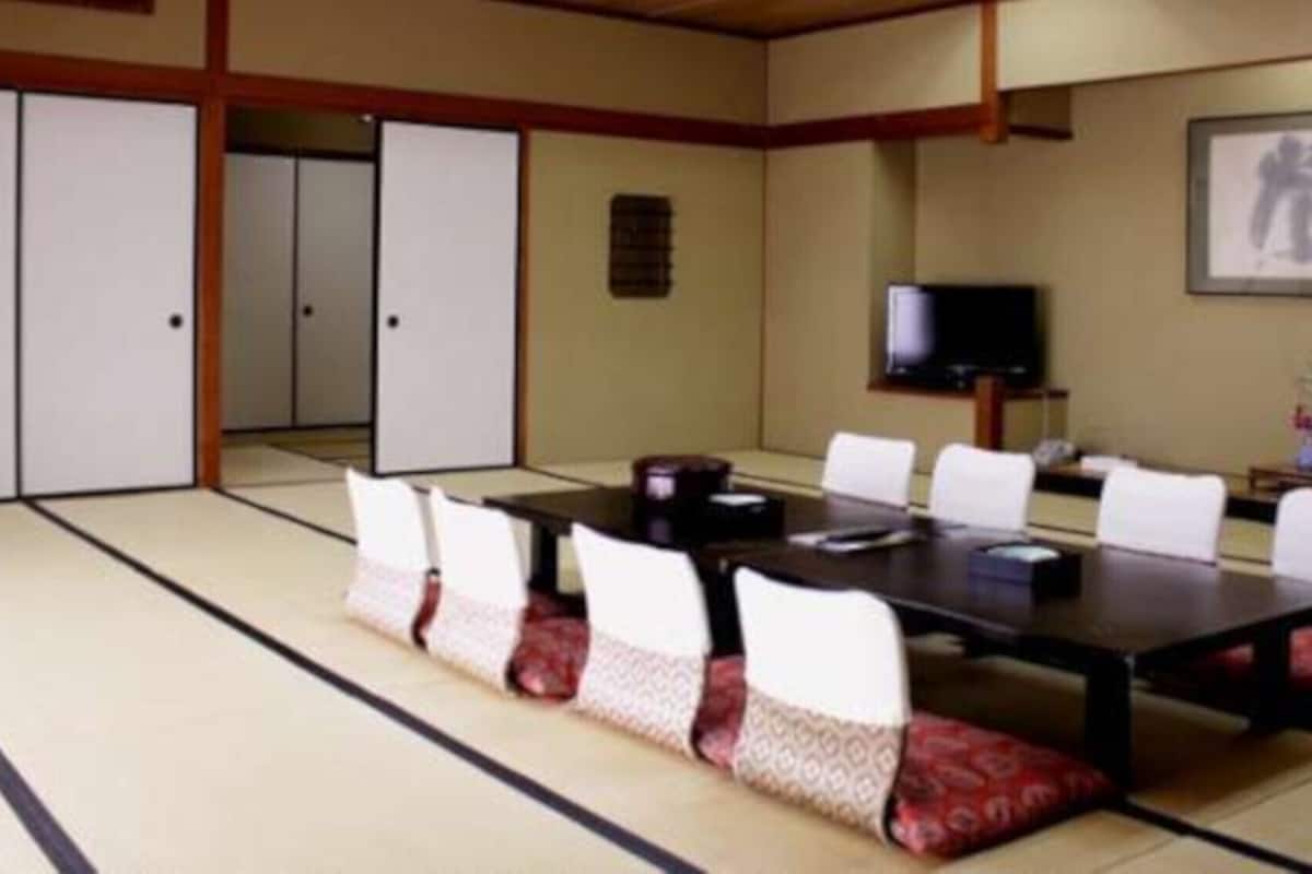 Ein traditioneller japanischer Raum mit Tatami-Böden, einem niedrigen Tisch und weißen Stühlen.