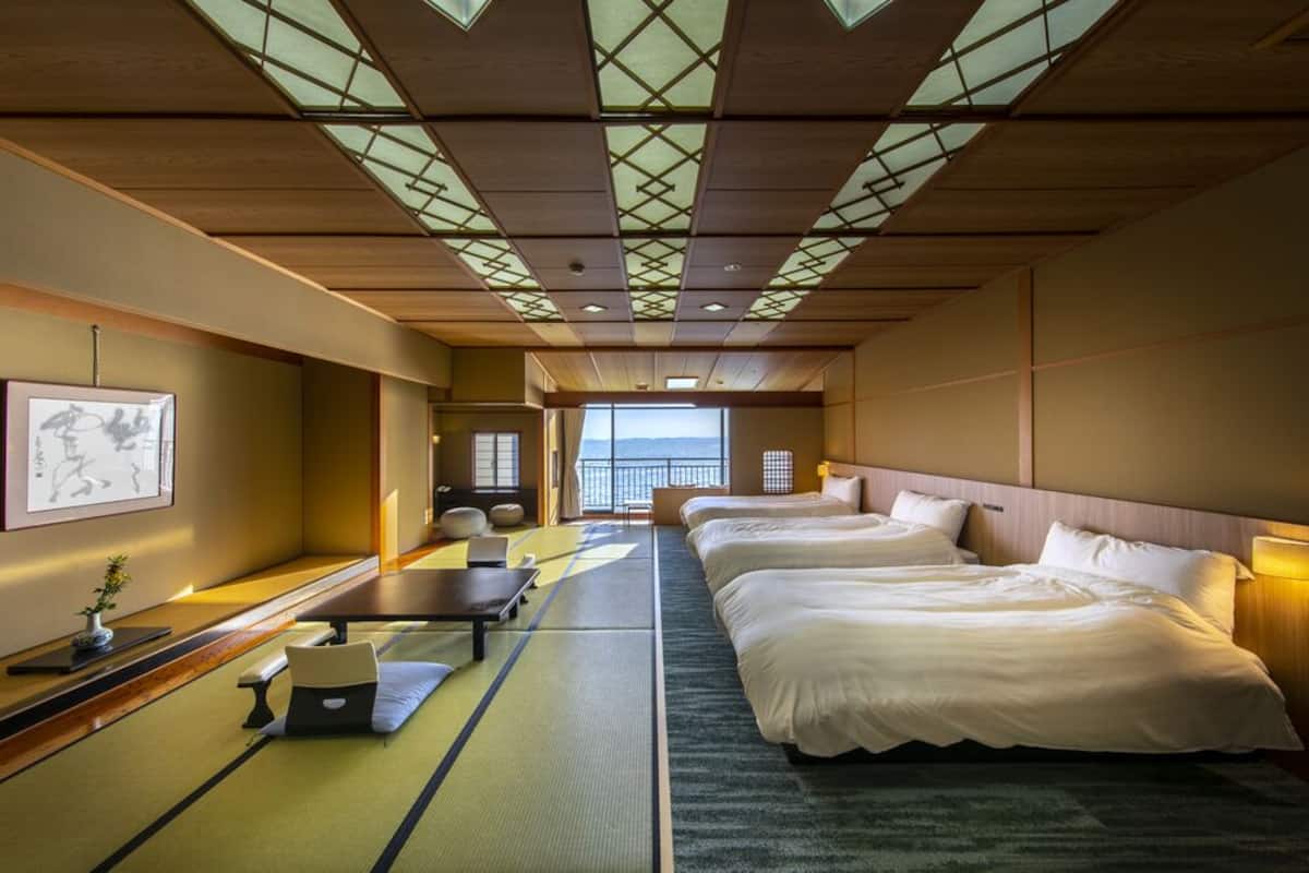 Ein traditioneller japanischer Raum mit Tatami-Böden, zwei Betten, einem Schreibtisch und Meerblick.