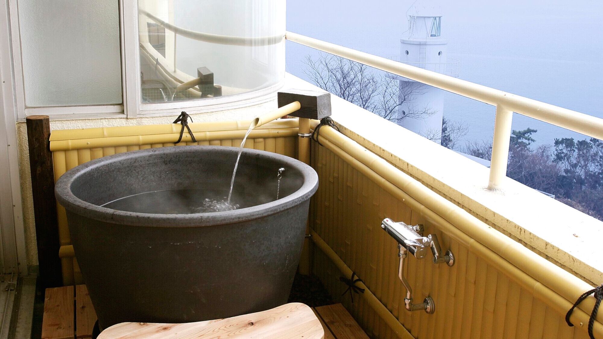 Un bain à remous avec un banc en bois, une fenêtre et une vue sur un phare.