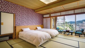 Una camera d'albergo con due letti, vista sulla città e pavimento tradizionale in tatami giapponesi.