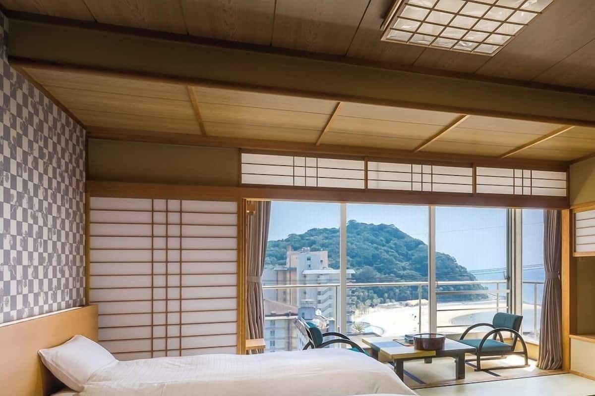 Ein Hotelzimmer mit zwei Betten, Bergblick und einem Sitzgelegenheit auf dem Balkon.