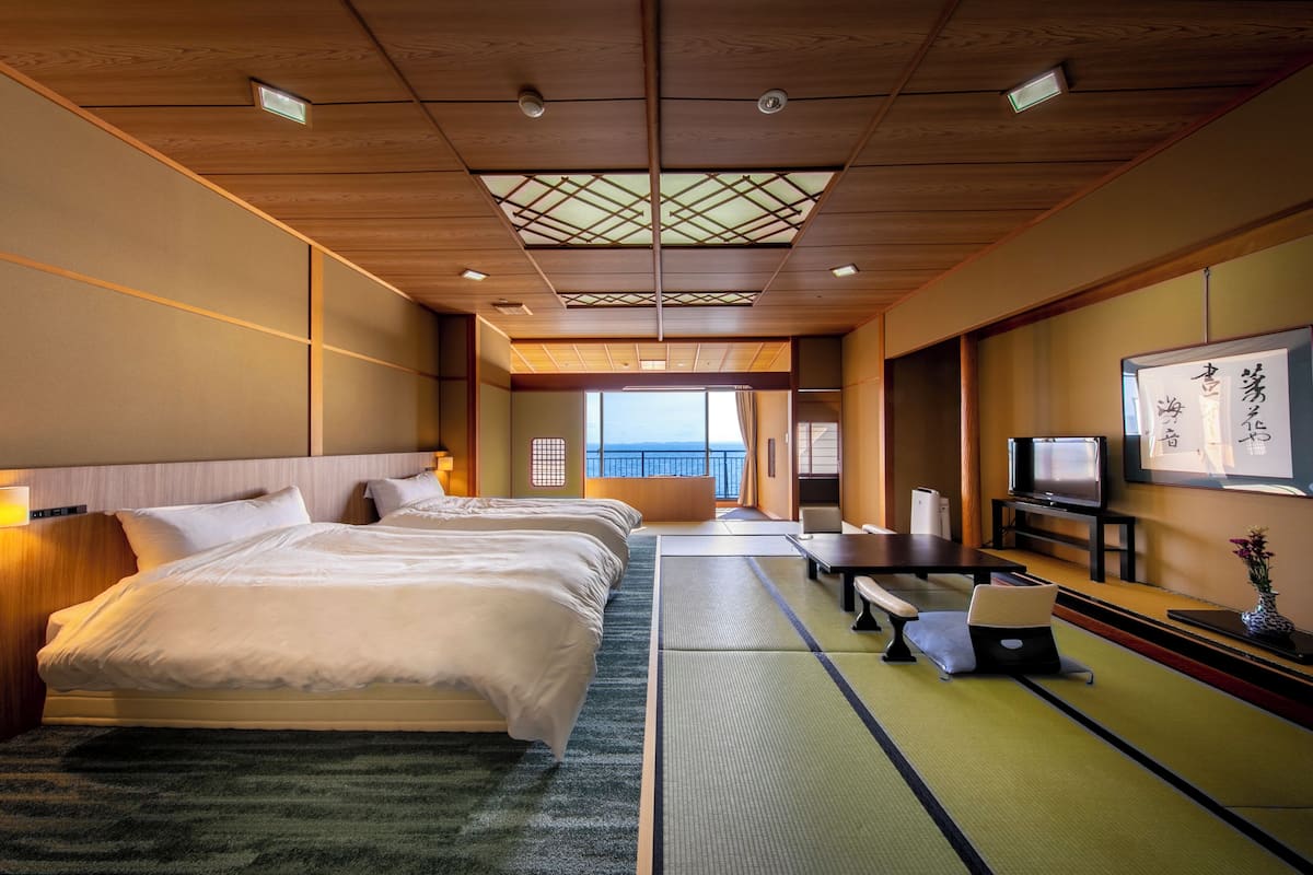 Ein Hotelzimmer mit einem großen Bett, einem Schreibtisch, einem Fernseher und Meerblick.