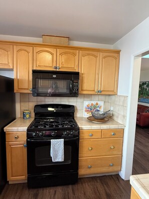 Kitchen area with a gas stove, microwave, and cabinetry.