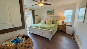 A bedroom with a bed, a ceiling fan, a nightstand, a lamp, and a window with blinds.
