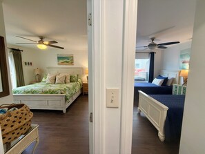 Two beds with distinct bedding, a ceiling fan, and a wall-mounted painting adorn this traditional room.