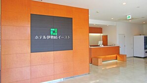 A reception area with a modern design, featuring a reception desk, a seating area, and a sign with Japanese text. - Hotel Isesaki East (Isesaki)