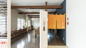 A spacious room with a wooden ceiling, a dining area with chairs and a table, and a corridor leading to another room. - Hotel Isesaki East (Isesaki)