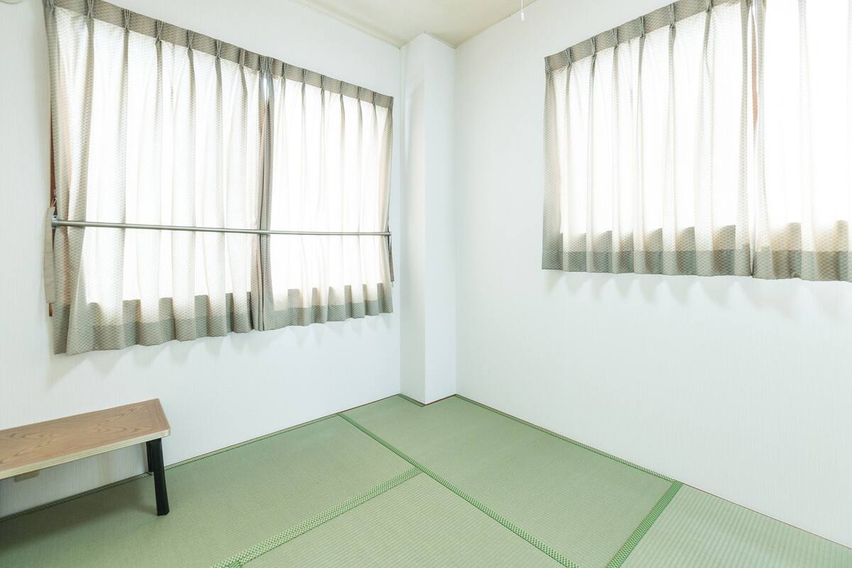 Ein Zimmer mit zwei Fenstern, einer Holzbk und Tatami-Böden.