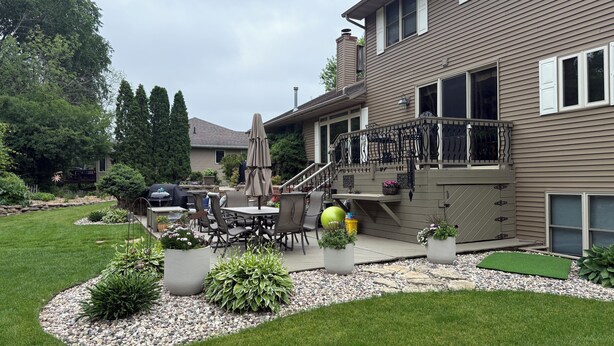 Une maison avec un patio, du mobilier d’extérieur et un petit jardin.