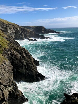A coastal landscape with rocky cliffs and turbulent ocean waves.