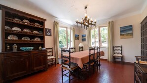 A dining room with a wooden table, chairs, a chandelier, and a cabinet with dishes. - Villa LE MENEZ for 10 persons with view on the marine lake (SOORTS HOSSEGOR)