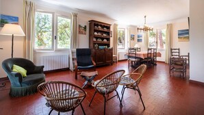 A spacious living room with a fireplace, a dining area with a table and chairs, and a large window with curtains. - Villa LE MENEZ for 10 persons with view on the marine lake (SOORTS HOSSEGOR)