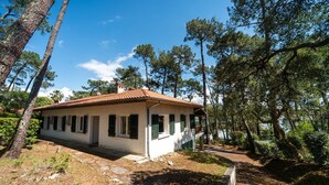 A single-story house with a tiled roof, surrounded by trees and a clear sky. - Villa LE MENEZ for 10 persons with view on the marine lake (SOORTS HOSSEGOR)