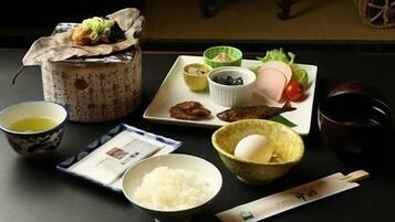 Un repas japonais traditionnel, composé d’un bol de riz, d’une tasse de thé et de différents plats disposés sur une table.