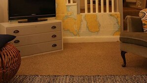 Una sala de estar con televisor, un mueble blanco, un mapa y una escalera.