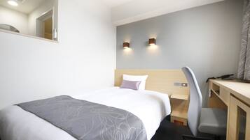 Habitación de hotel con cama, escritorio y dos luces fijadas a la pared.