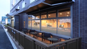 Ein Restaurant mit Außenbereich, großen Fenstern und einer Ziegel-Fassade.