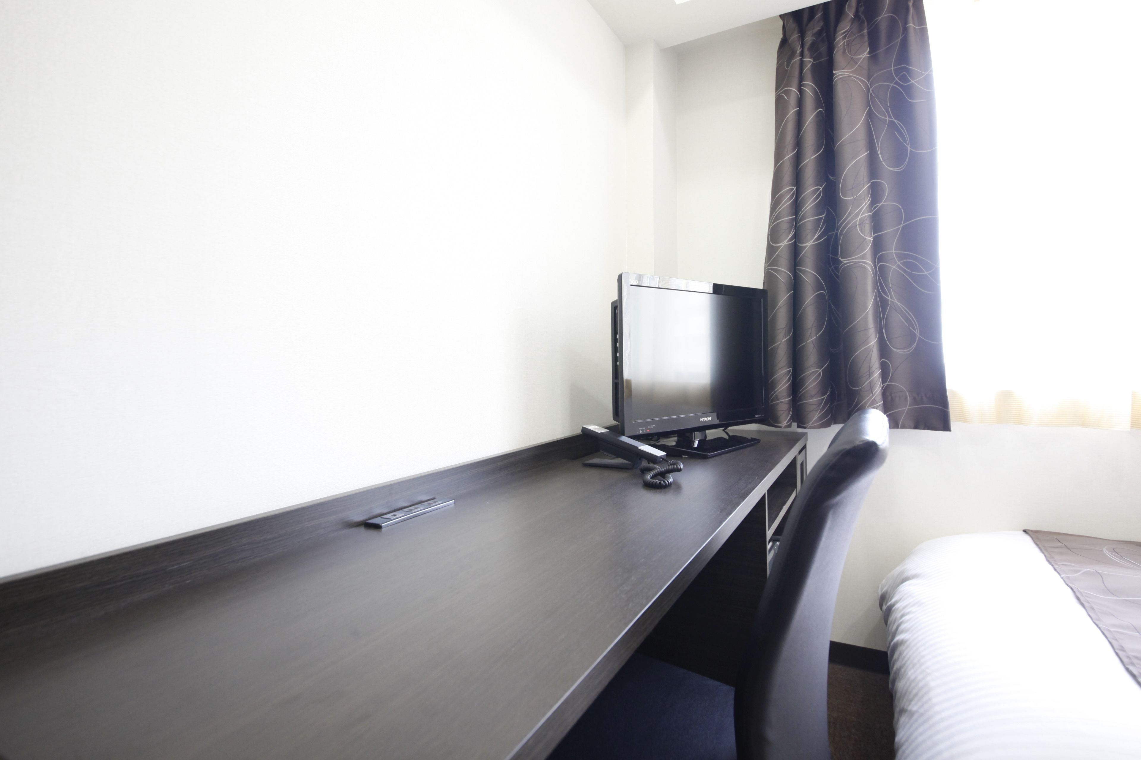 Una habitación de hotel con un escritorio de madera oscura, un monitor de computadora y una silla.